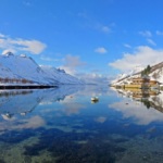 A panoramic view of the breathtaking landscape of the Ersfjord in Norway. The mirror effect on the water is incredible.