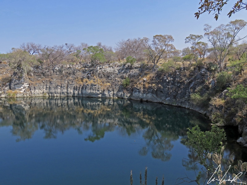 The lake Otjikoto is an expanse of turquoise water well hidden from sight. It looks like a deep circular hole surrounded by steep, 65-foot dolomite walls.