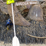 On a simple wooden sign, the sentence "welcome to Angola" is written with white letters. This sign indicates that we have crossed the border.