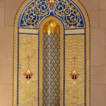 Dans les couloirs à arcades de la Grande Mosquée du Sultan Qaboos ce décor bleu et or évoque les mosaïques du Dôme du Rocher à Jérusalem.