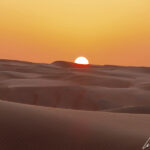 Aux premières heures du jour, les dunes du Wahiba Sands se colorent de dégradés d’orange sous un ciel lui aussi orangé.