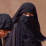 These two Omani women wear the traditional black, chic and dark abaya, most of them with the veil, the hijab.