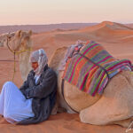 With his back against his camel, his feet hidden in the sand, our Bedouin guide seems to enjoy the moment.