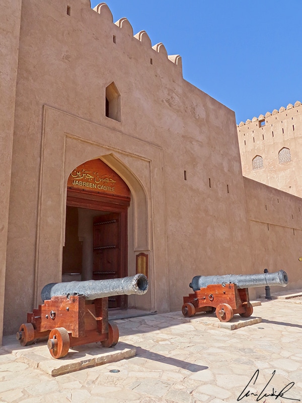 The main gate of Jabrin Castle is set between thick defensive walls and is flanked by two cannons.