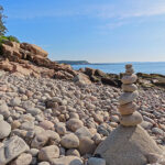 A cairn on Acadia National Park beach. These piles of stone are delicately balanced. Does the cairn indicate the path to follow ?