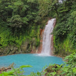 The beautiful Rio Celest waterfall plunges 98 feet into a pool of bright blue water surrounded by dense tropical forest.