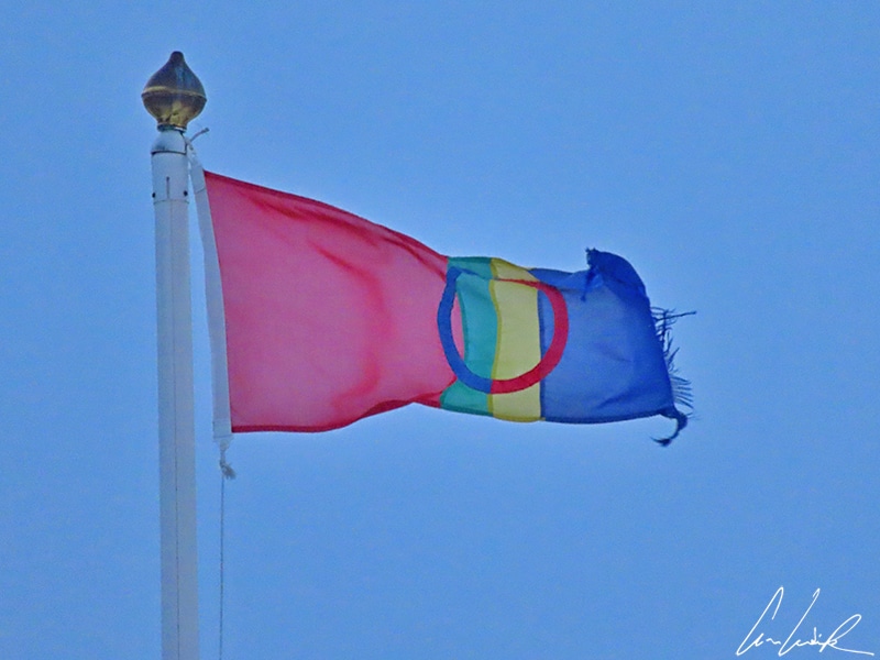 Le drapeau de la Laponie ou drapeau Sámi flottant au vent. Il est reconnaissable à son anneau et à ses couleurs « gákti » (vêtement traditionnel sami): bleu, rouge vert et jaune.