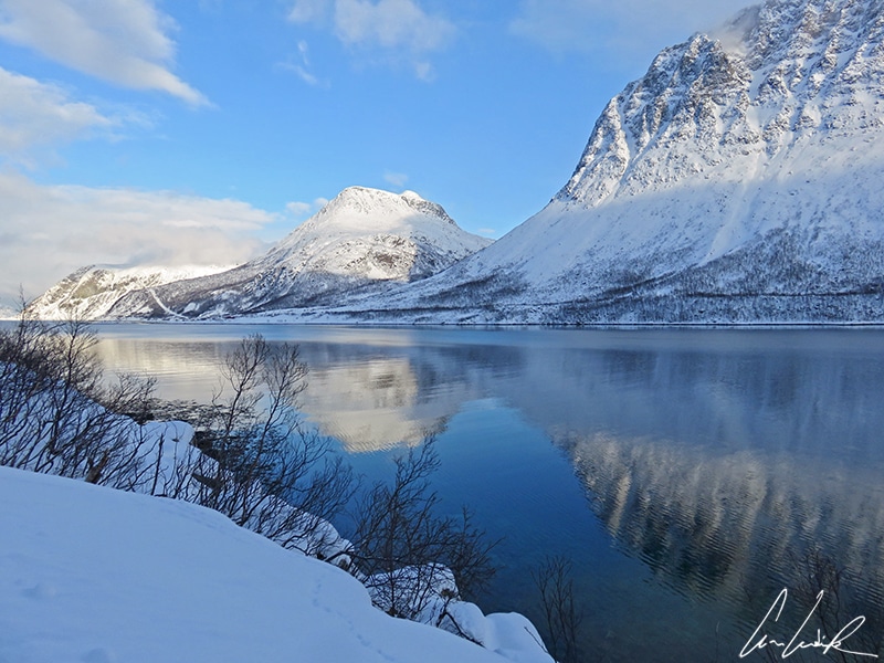 Les majestueux fjords de la Laponie norvégienne en hiver. Les montagnes se reflètent dans les eaux du fjord sous un beau ciel bleu.