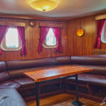 Le salon cosy et chaleureux de l’Arctic Explorer avec ses banquettes confortables et ses tables en bois.