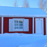 A red cottage in Gammelstad, with its white door and window sills. The houses are very tiny.