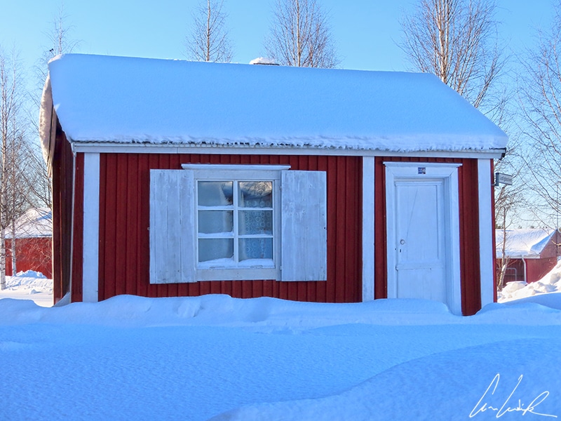 A red cottage in Gammelstad, with its white door and window sills. The houses are very tiny.