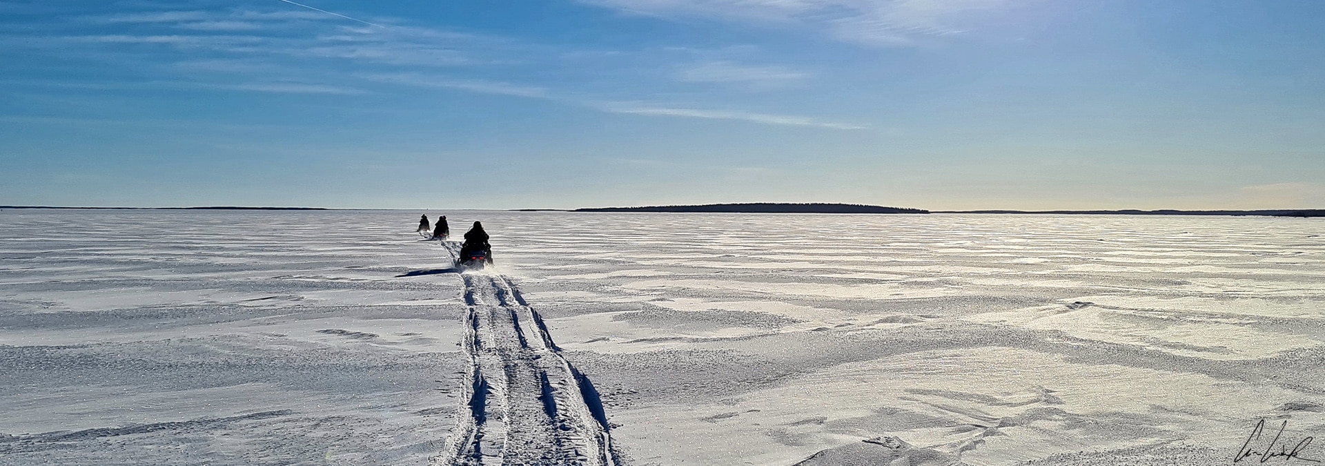 The snowmobile tour starts over a frozen sea, an enormous white expanse as far as the eye can see.