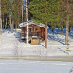 A little house nestled in the forest by the water waiting for summer vacationers.